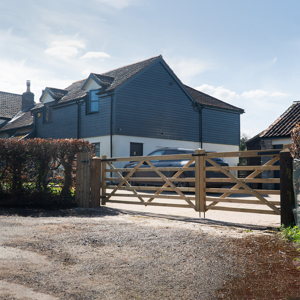 Lifestyle shot of Extra Bottom Bar Diamond Brace Planed Gate installed in driveway 