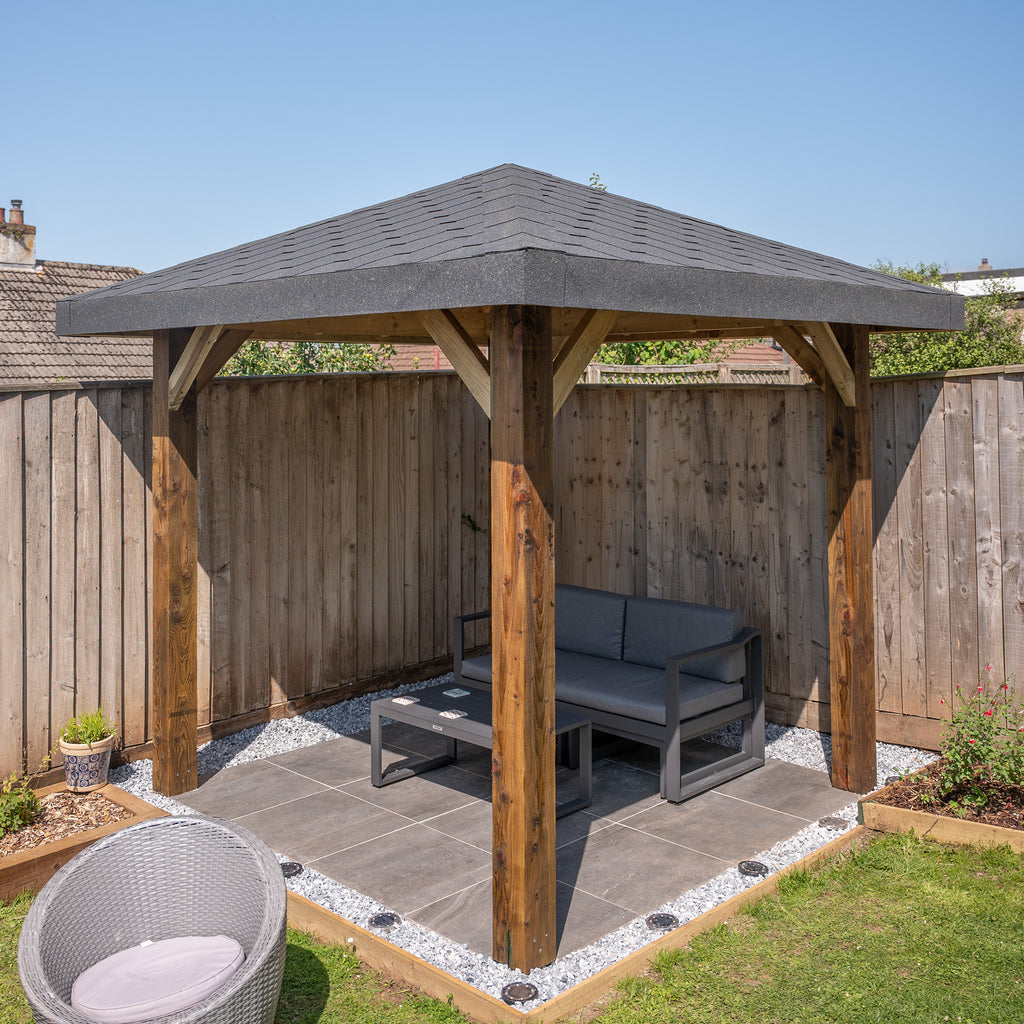 Lifestyle image of 4 pitch pergola with Katepal Grey shingle roof, installed in garden setting 