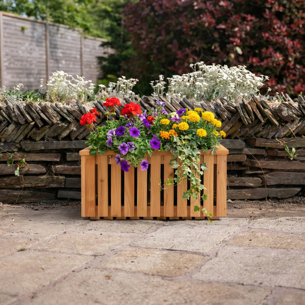 Lifestyle picture of planter installed in a garden setting, with flowers 